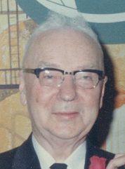 A close up of a man, Dr. Bryce A Brown (founder of Kedron Dells Golf Club), wearing glasses and a suit and tie.