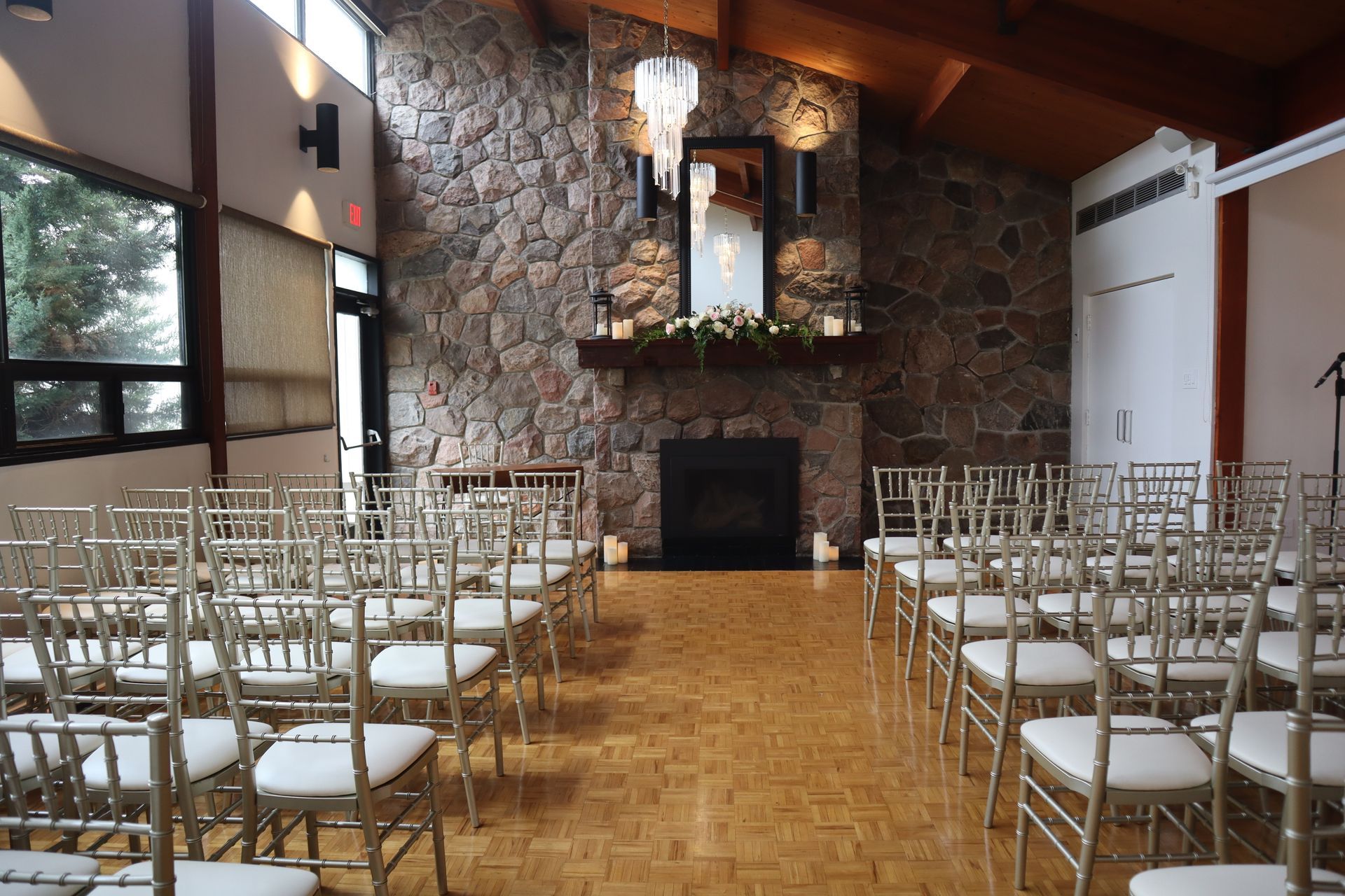 Rows of chairs are lined up in a room with a fireplace for a wedding ceremony.