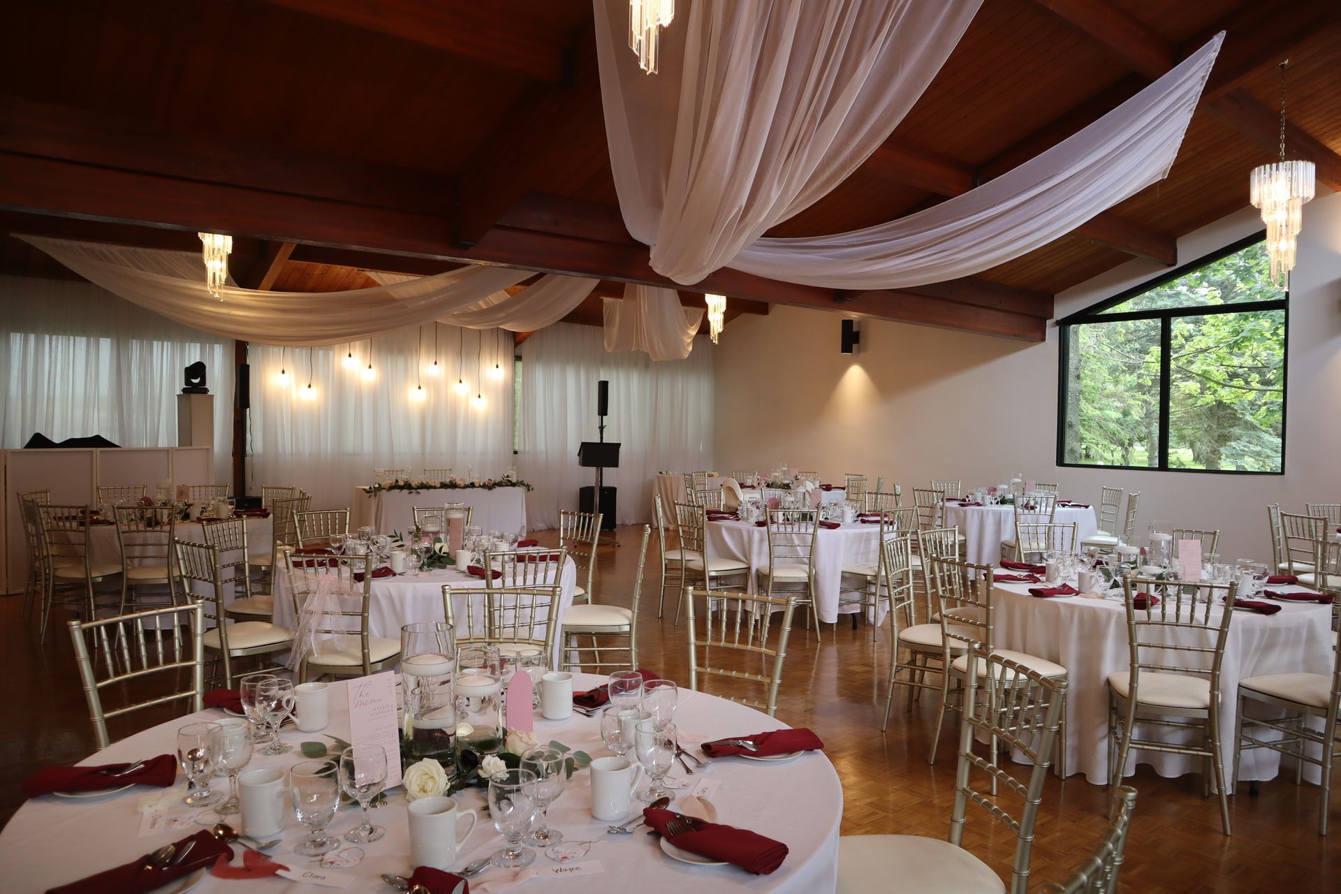 A large room with tables and chairs set up for a wedding reception