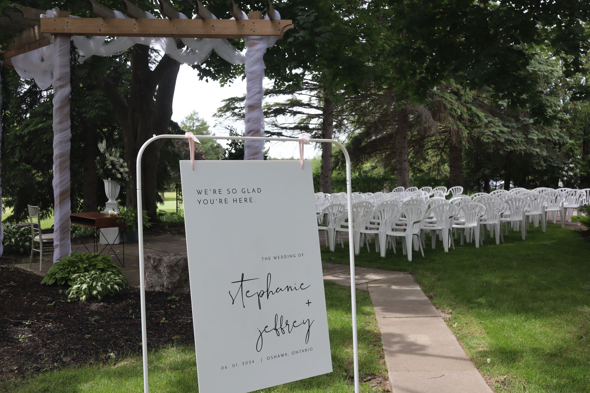 A white sign wedding sign with a ceremony space in the background.