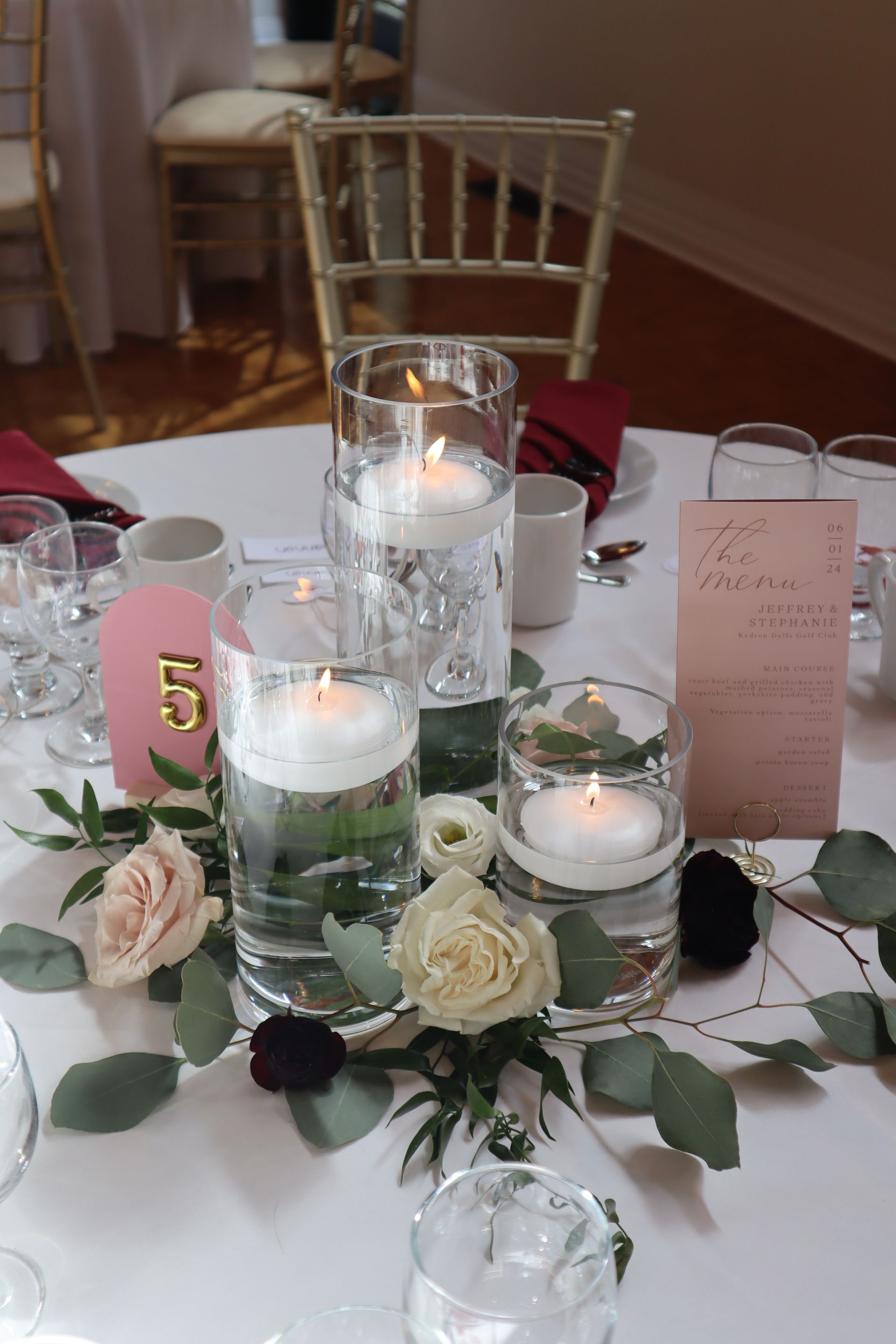 A table with floating candles and flowers as a centre piece and a table number.