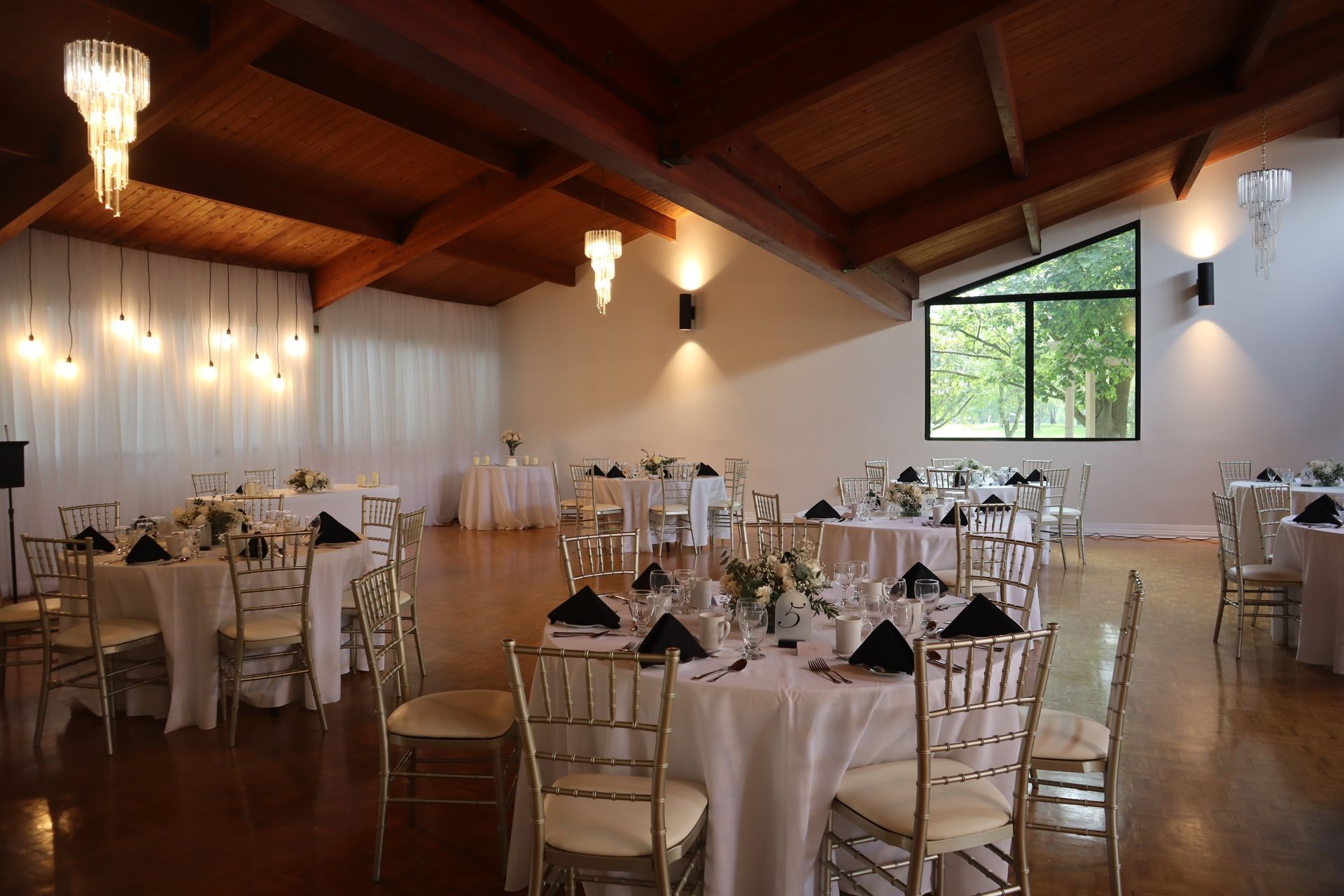 A large room with tables and chairs set up for a wedding reception.