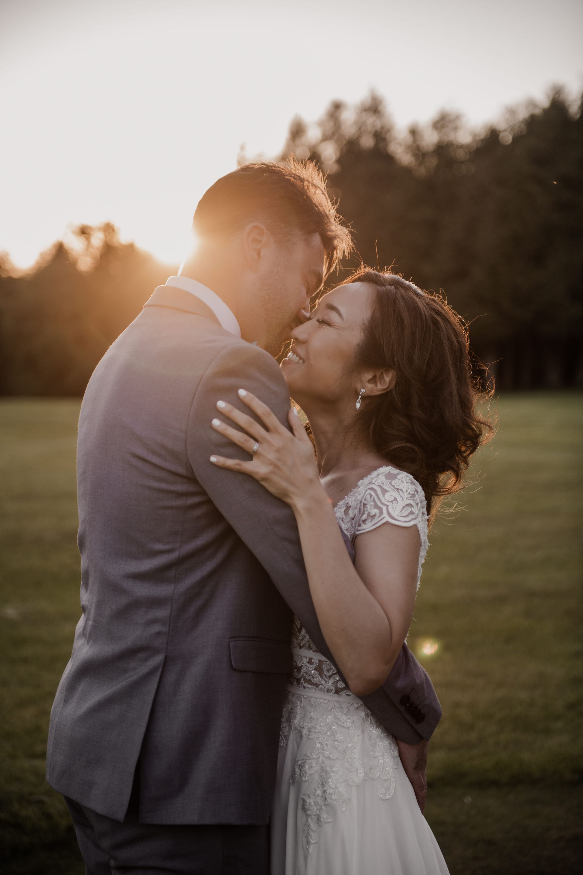 A bride and groom are hugging each other on a golf course at sunset.