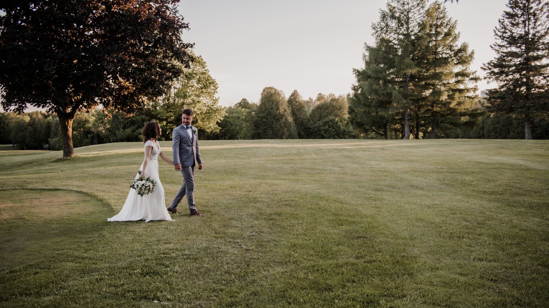 A bride and groom are walking through a golf course.