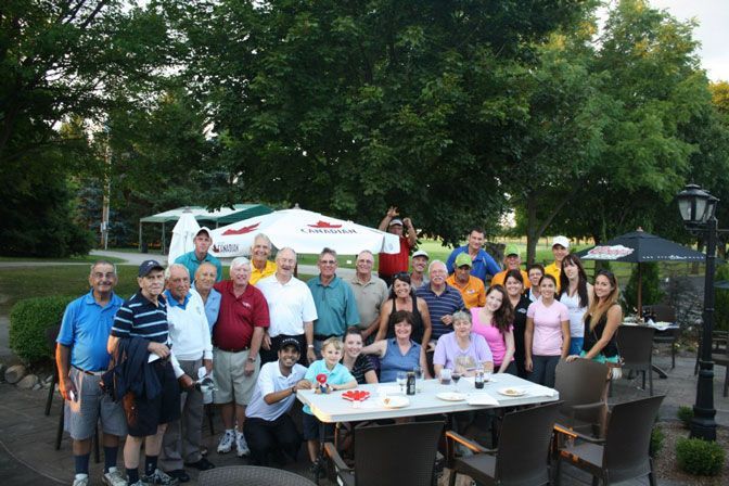 A group of people standing around a table with umbrellas in the background