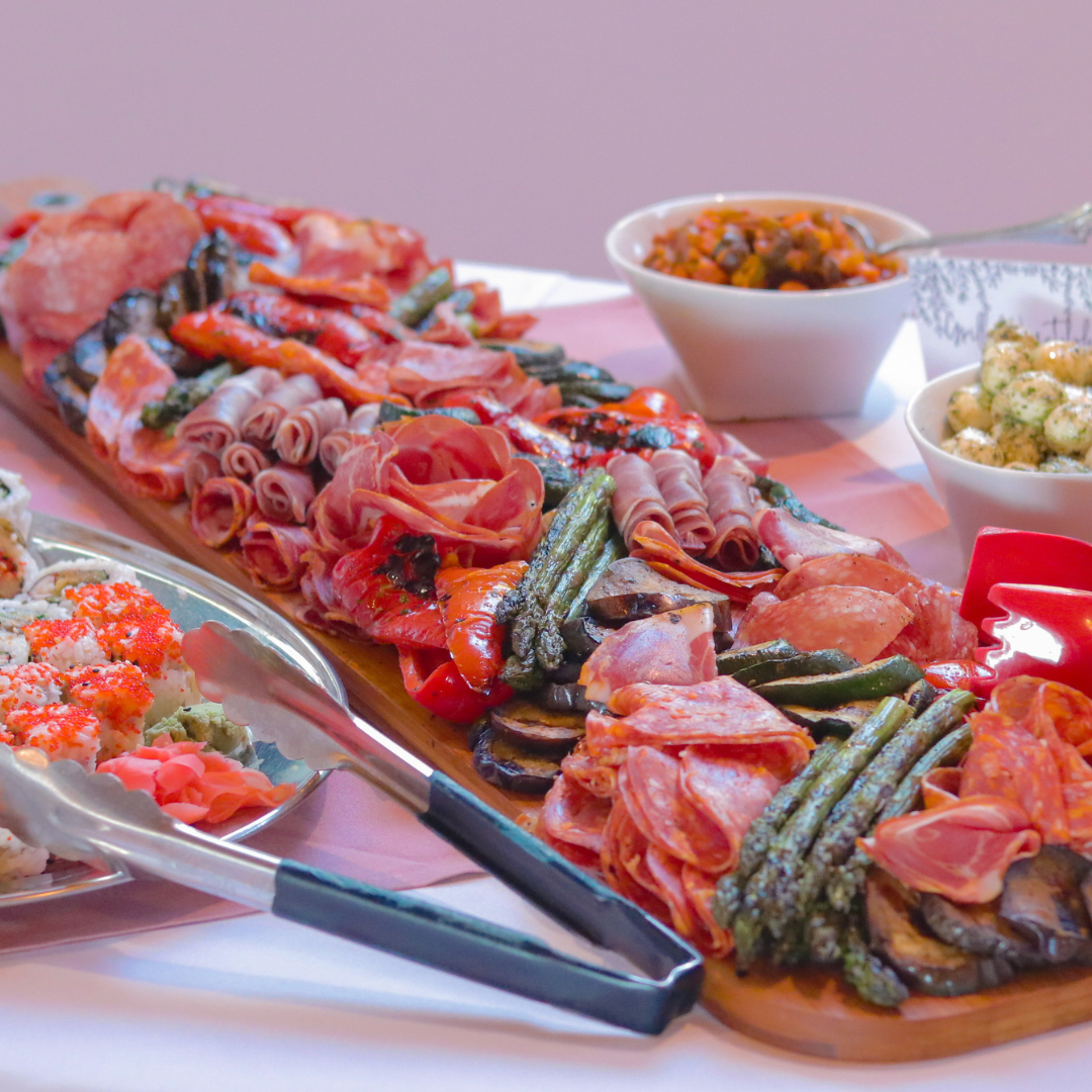 A wooden charcuterie board filled with meat and vegetables on a table.