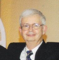 A man, Robert Brown, in a suit and tie is smiling for the camera.
