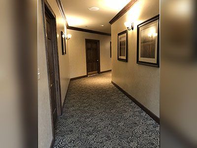 a long hallway with a carpeted floor and pictures on the wall.