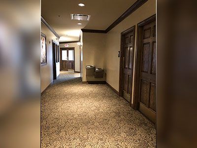 a long hallway with a carpeted floor and wooden doors.