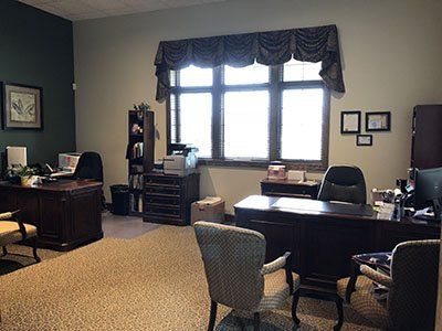 a large office with a desk, chairs, and a large window.