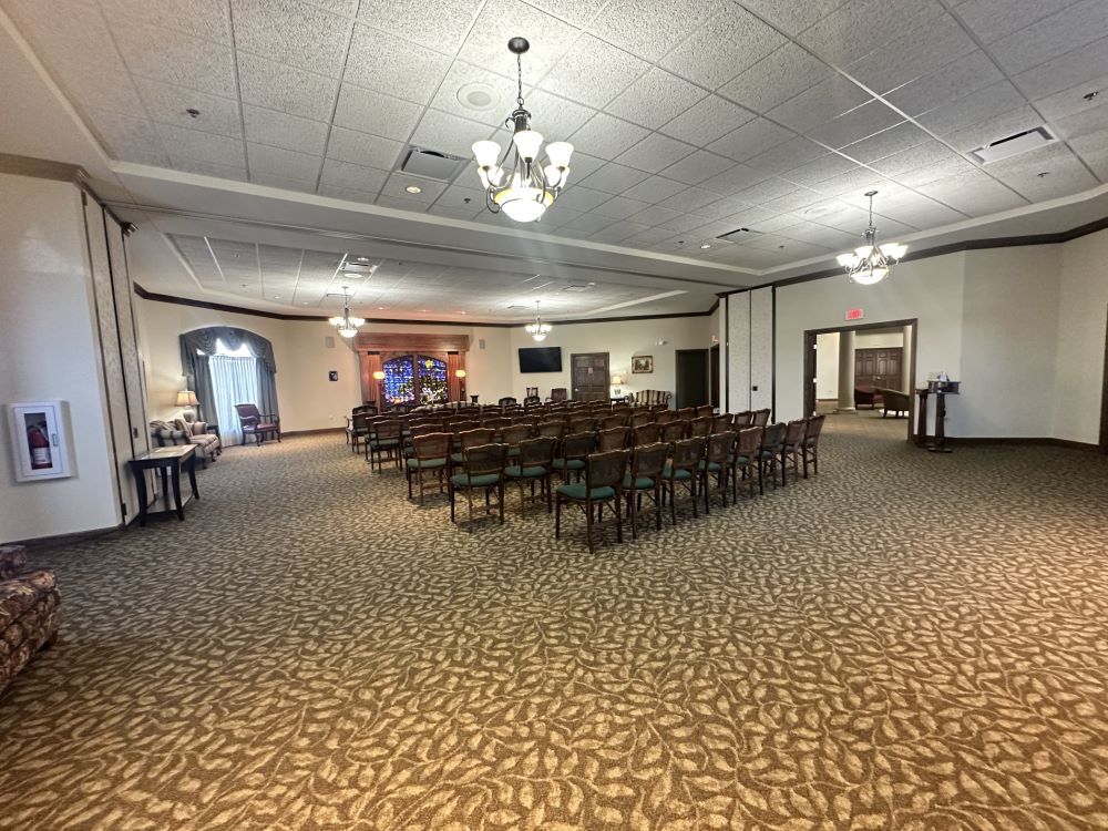 a large room with rows of chairs and a stained glass window