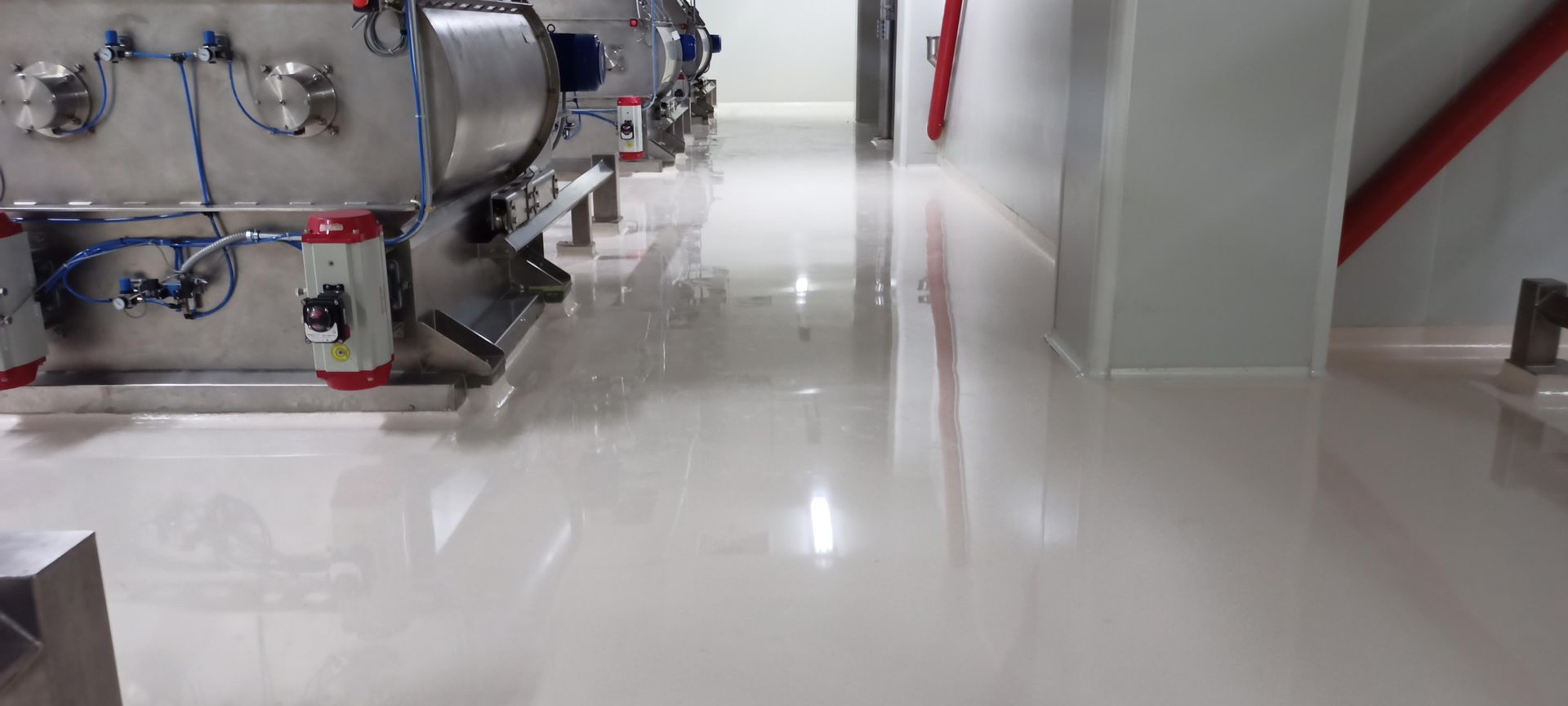 Shiny, white industrial floor with machinery on the left. 