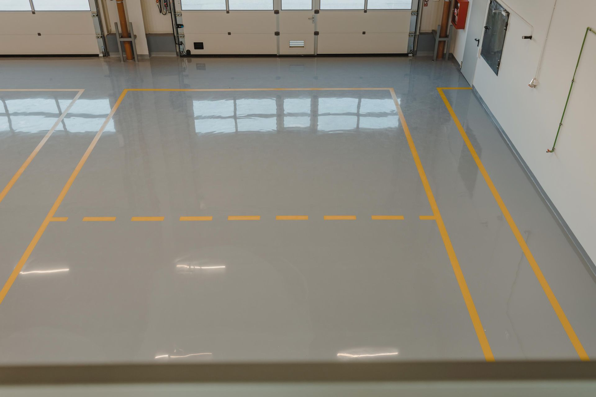 Indoor area with grey floor and yellow lines, possibly for sports or parking.