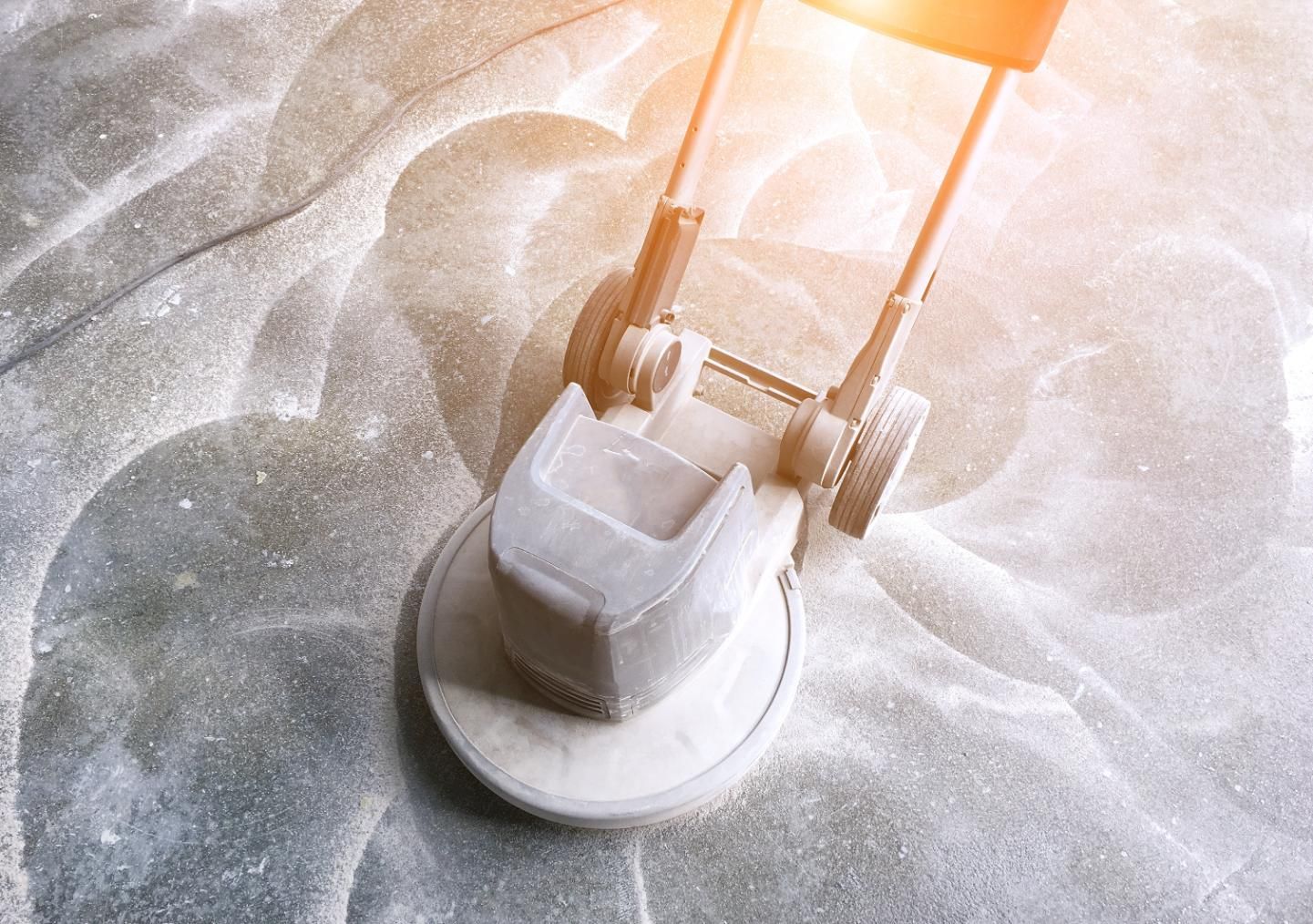 Floor polisher cleaning a light-colored surface with swirling patterns.