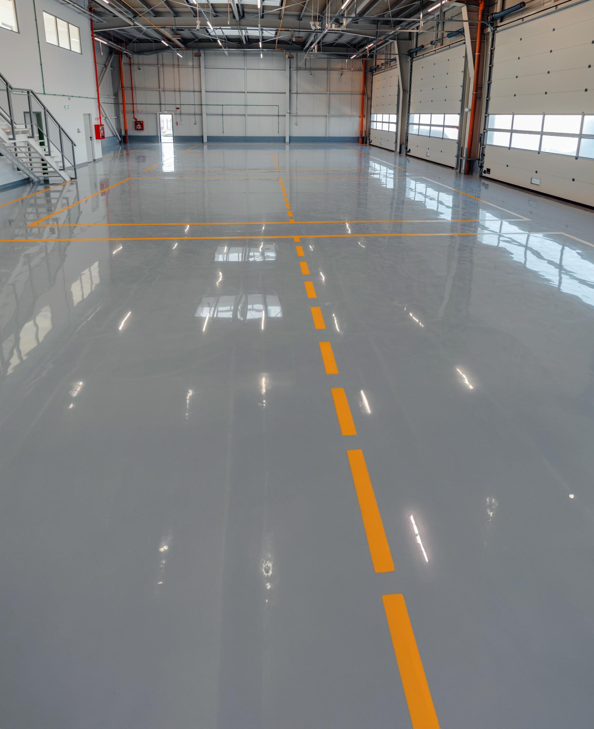 Inside a gray, shiny industrial space, with a yellow line on the floor.