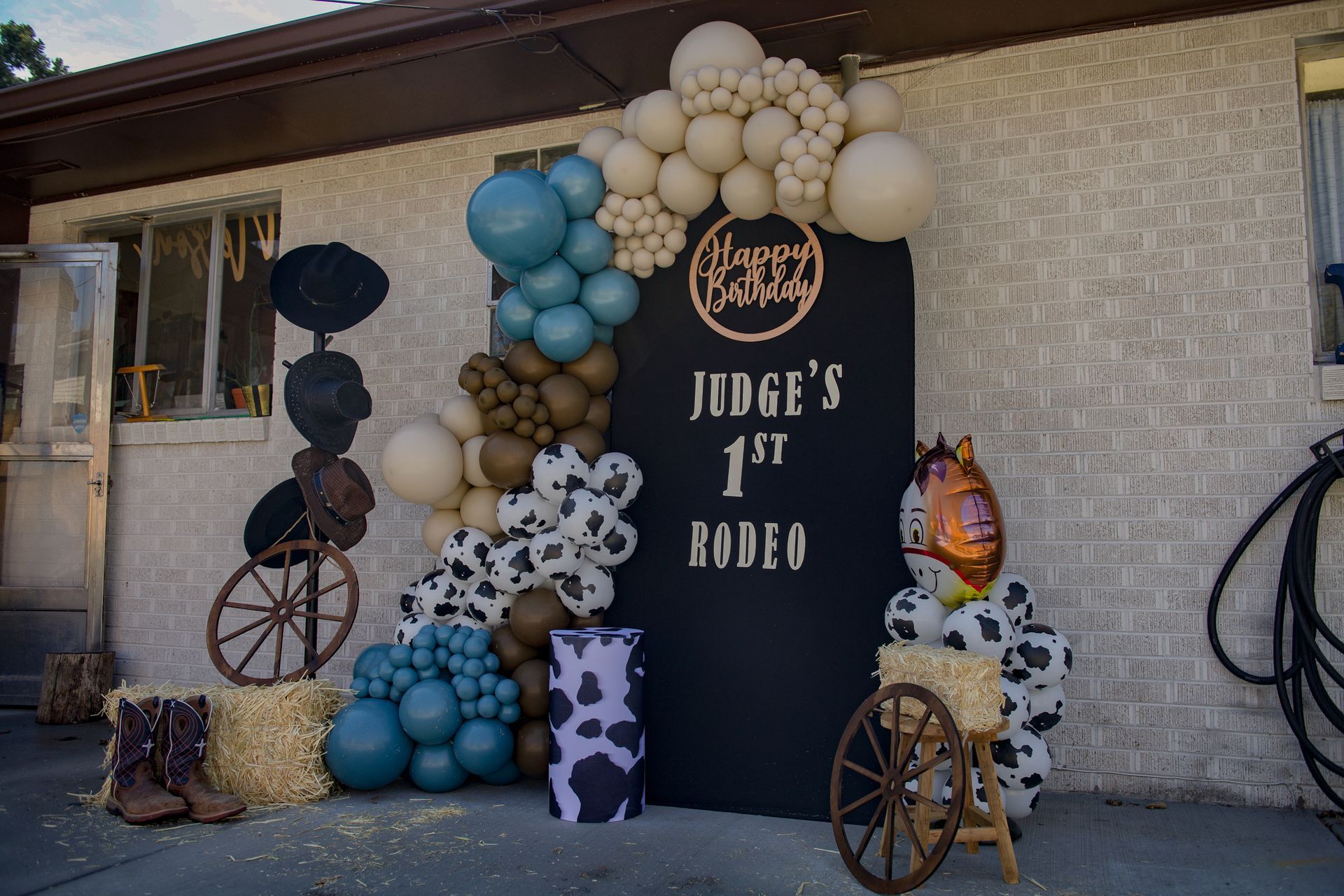 A sign that says `` judge 's 1st rodeo '' is surrounded by balloons and hay bales.