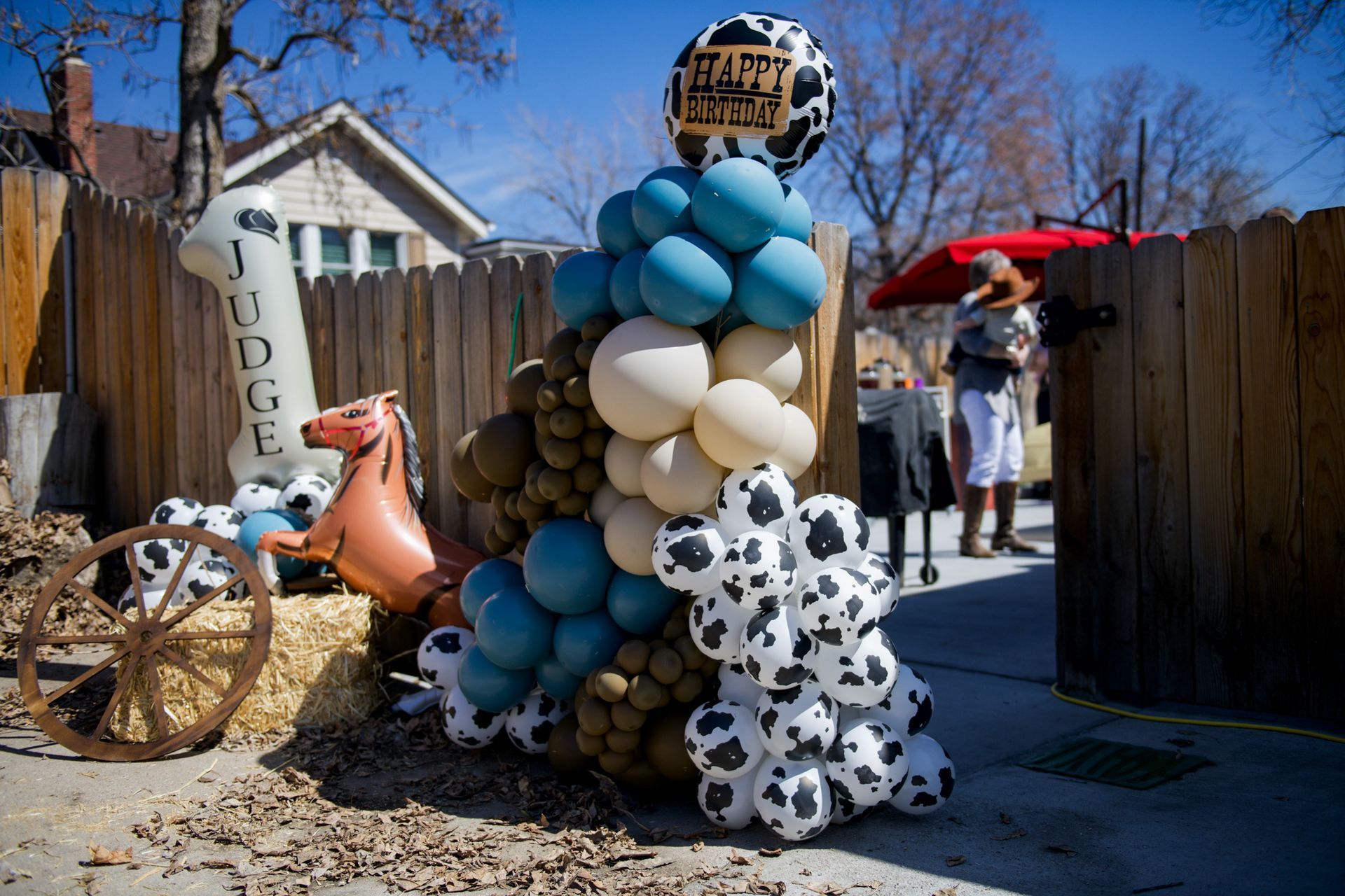 A bunch of balloons are stacked on top of each other in front of a wooden fence.