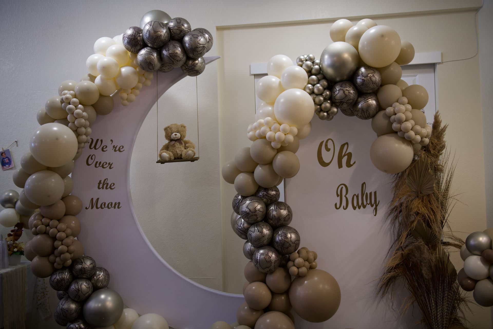 A crescent moon is decorated with balloons for a baby shower.