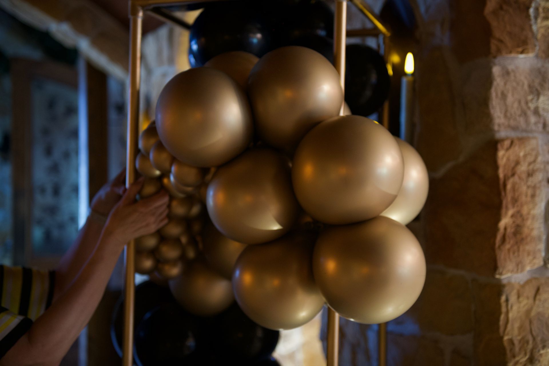 A person is holding a bunch of gold and black balloons.