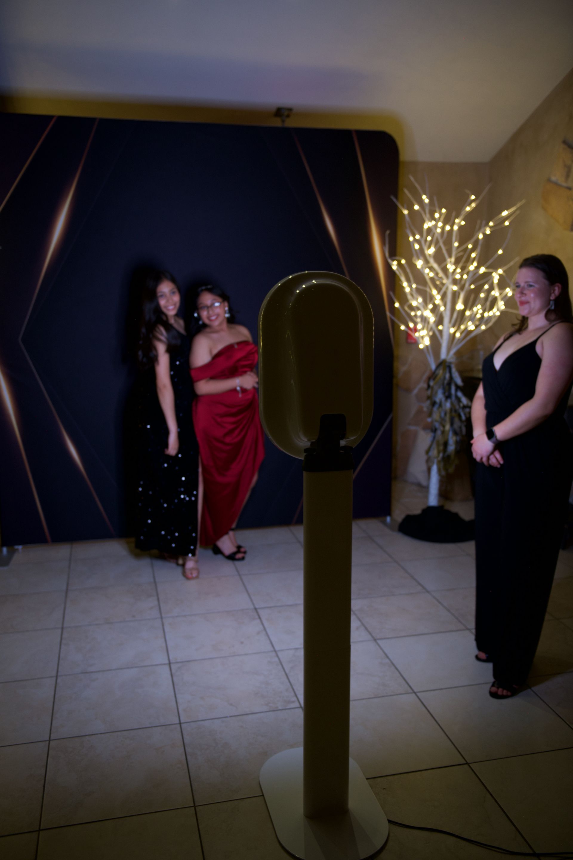 Three women are posing for a picture in front of a photo booth.