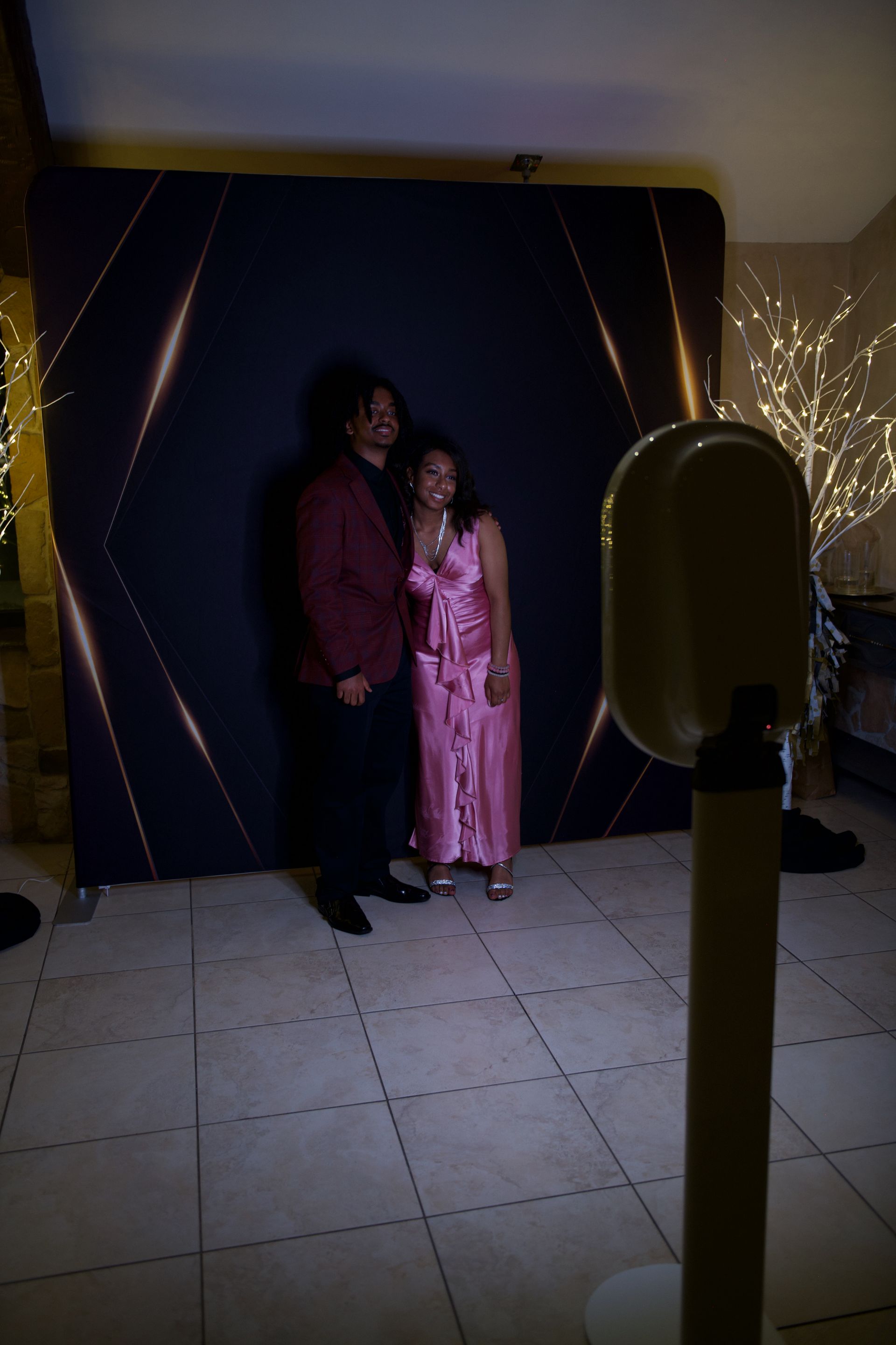 A man and a woman are posing for a picture in front of a photo booth.