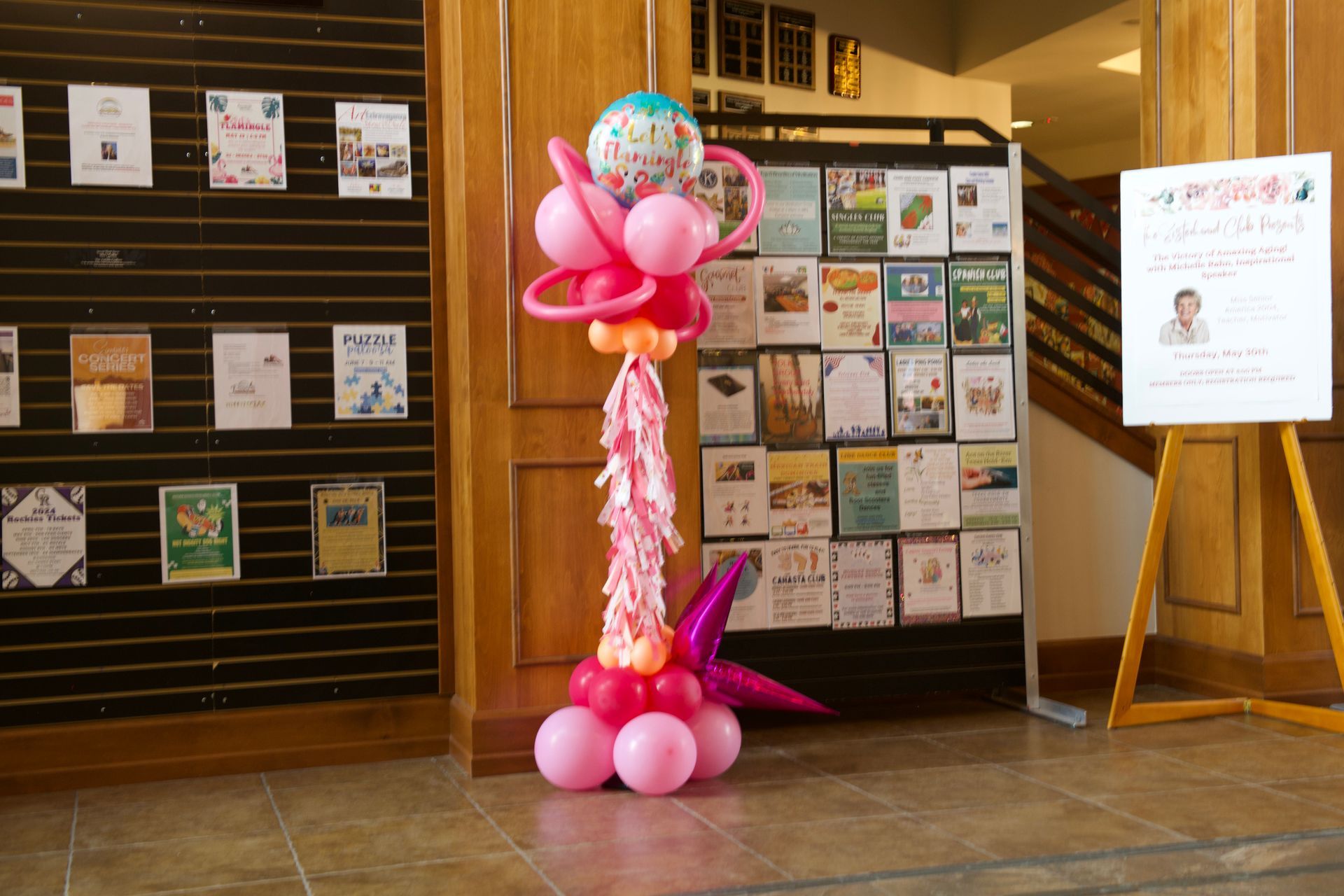 A bunch of pink balloons on a stand in a hallway