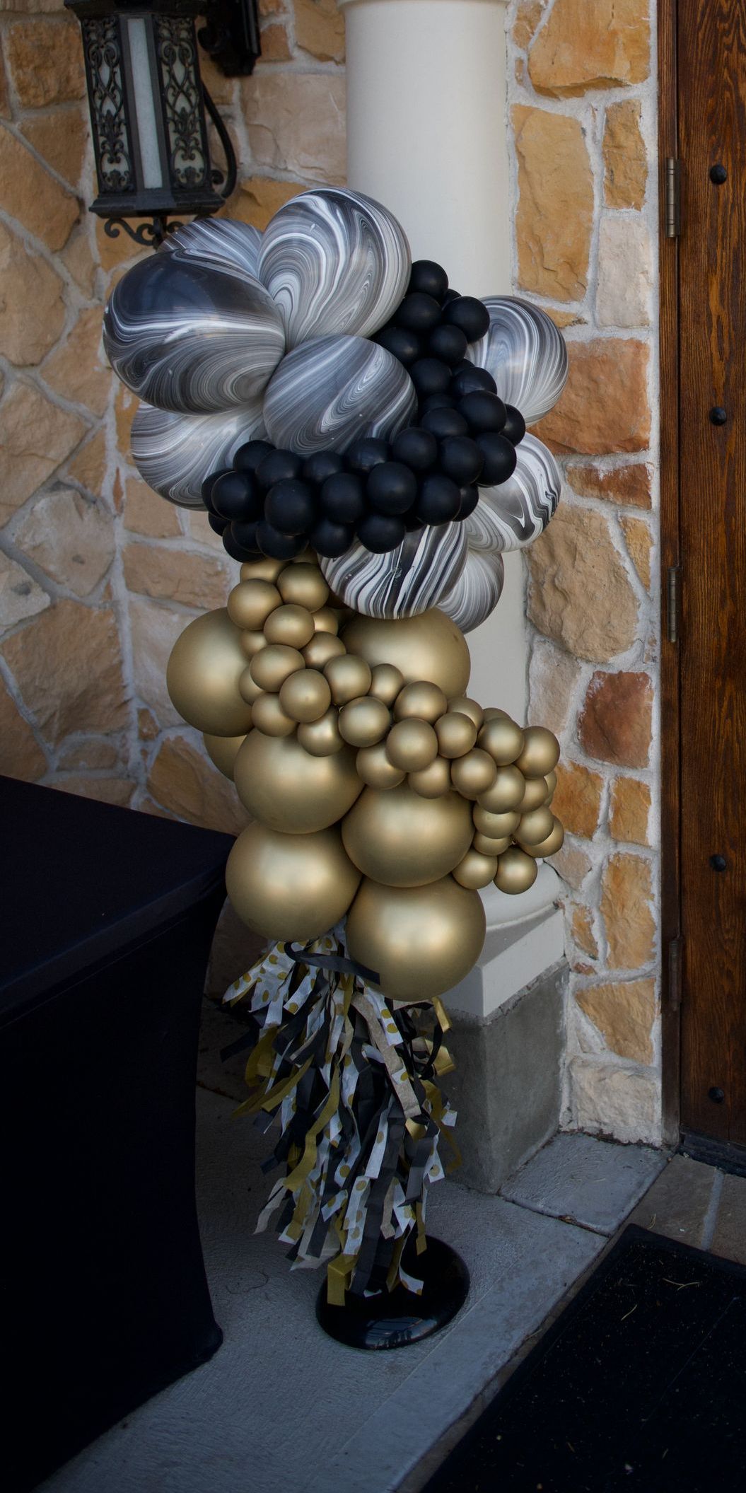 A bunch of balloons are sitting on the porch of a house.