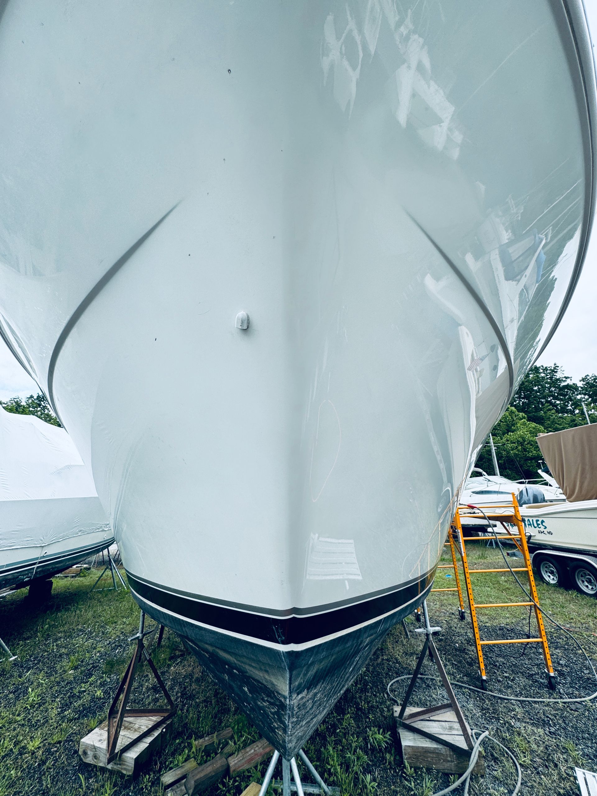 The front of a white boat is sitting on a dock.