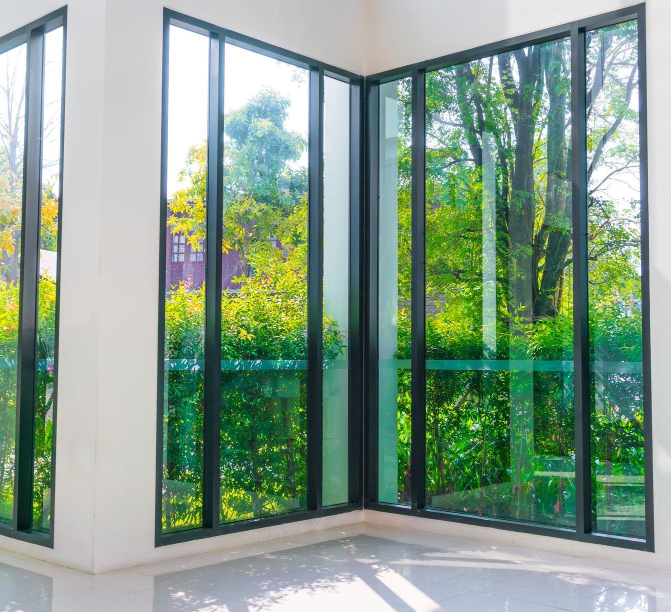 A room with a lot of windows and trees in the background.