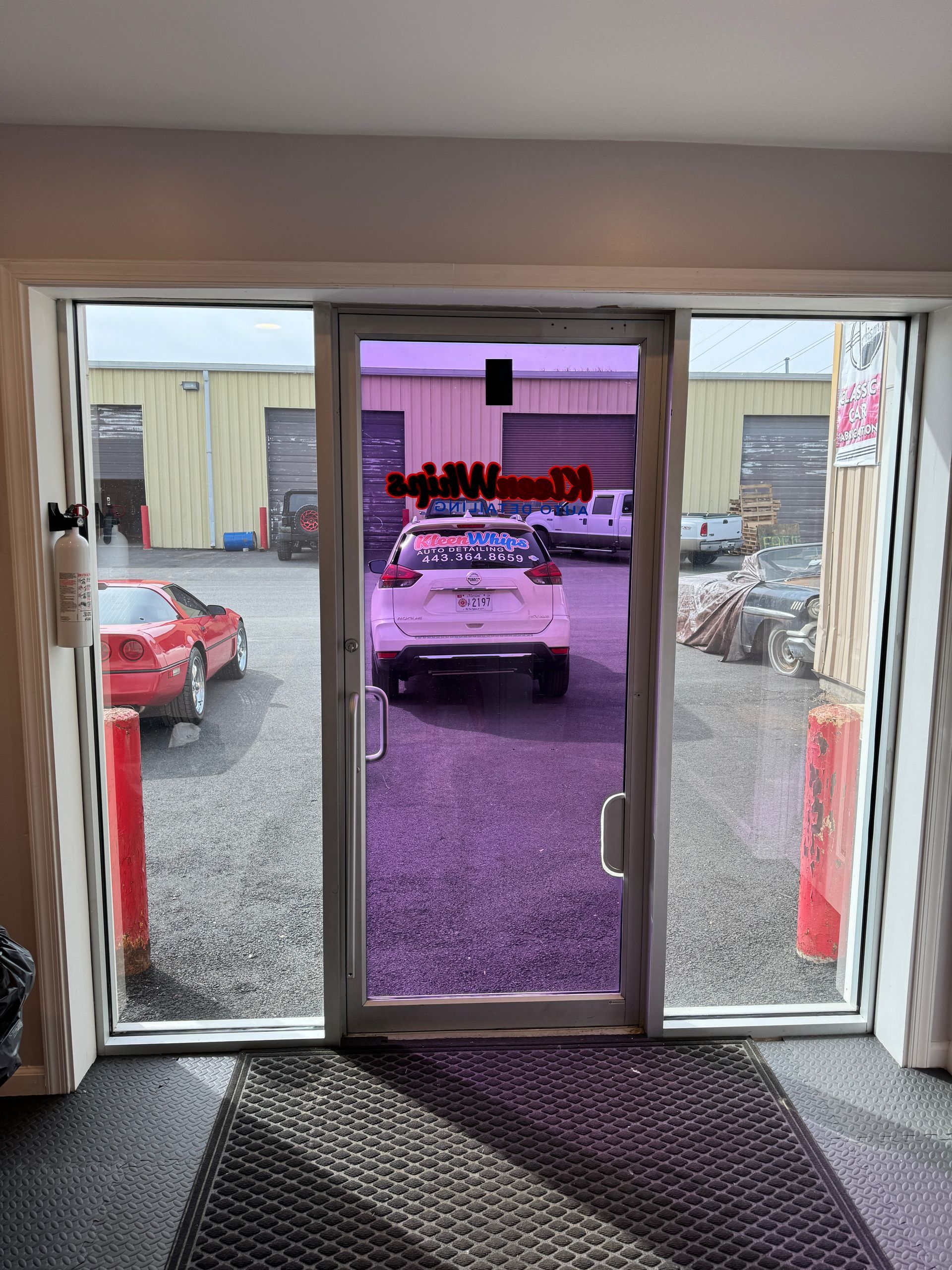 A car is parked in front of a glass door in a garage.