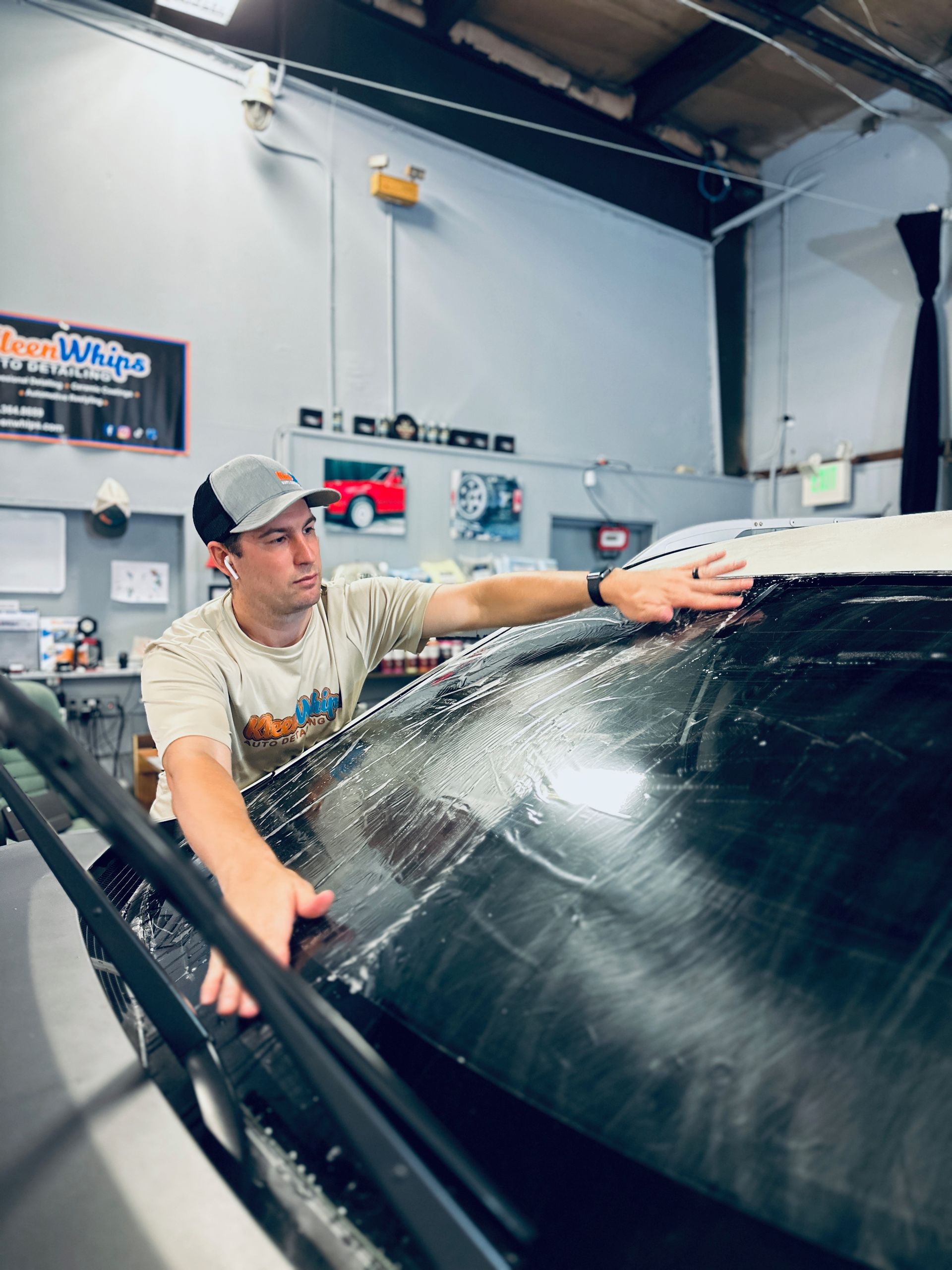 A man is cleaning the windshield of a car in a garage.