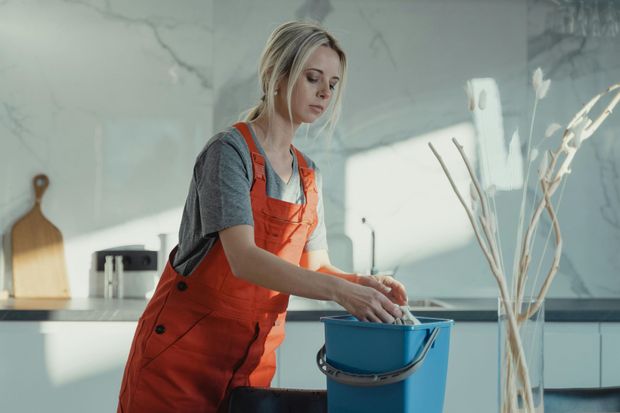 Yellow-gloved hand wiping a surface with a white cloth in a bright room