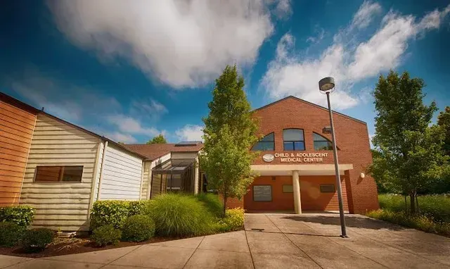 Exterior view of a brick medical center building with a light-colored siding section on the left.
