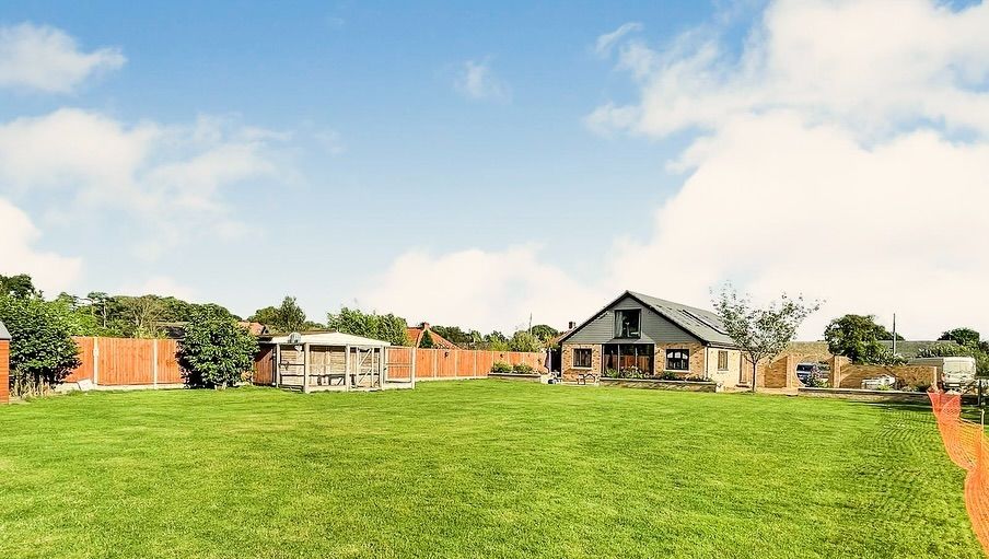 A large lush green field with a house in the background.
