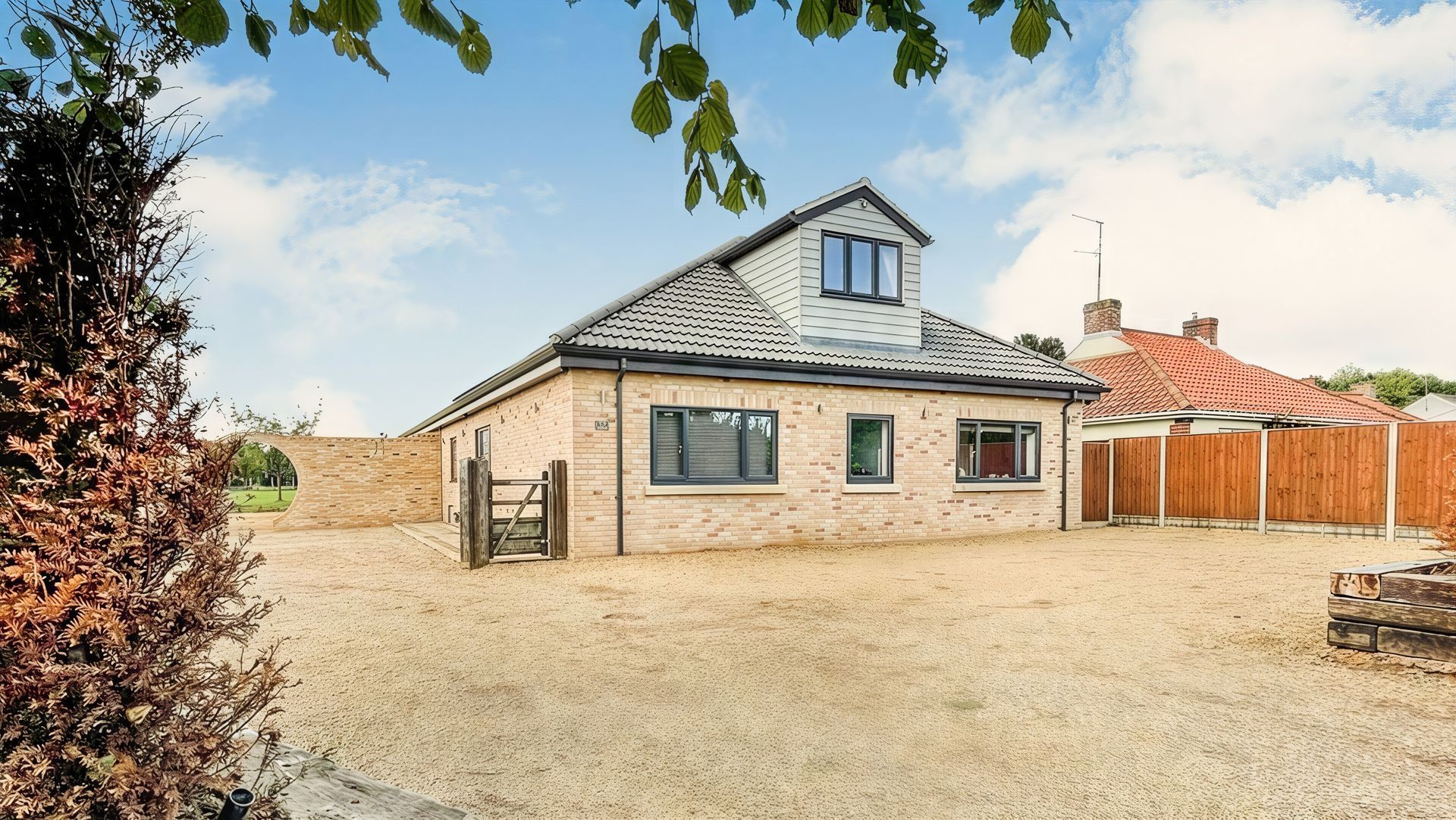 A house with a lot of windows and a gravel driveway in front of it.