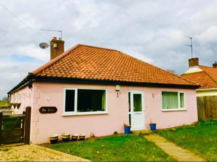 A pink house with a red tile roof and a white door