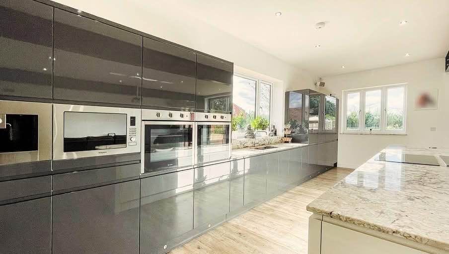 A kitchen with gray cabinets , stainless steel appliances , a sink , and a microwave.
