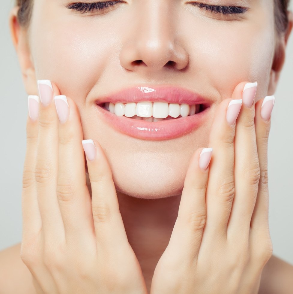 image of woman smiling with hands on face