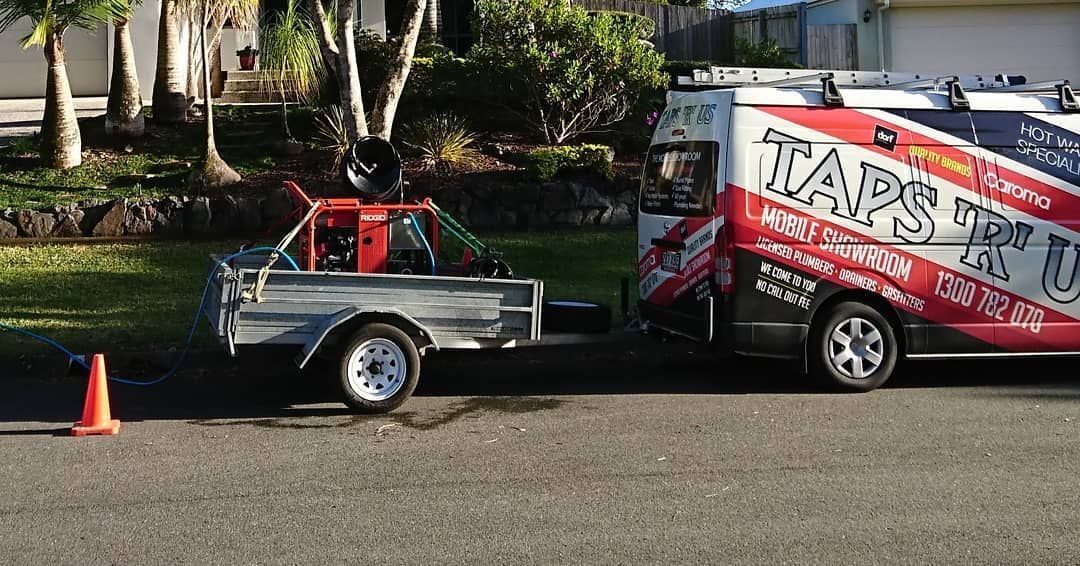 A trailer carrying equipment is hitched to a branded van parked on a street — Taps 'R' Us in Kunda Park, QLD