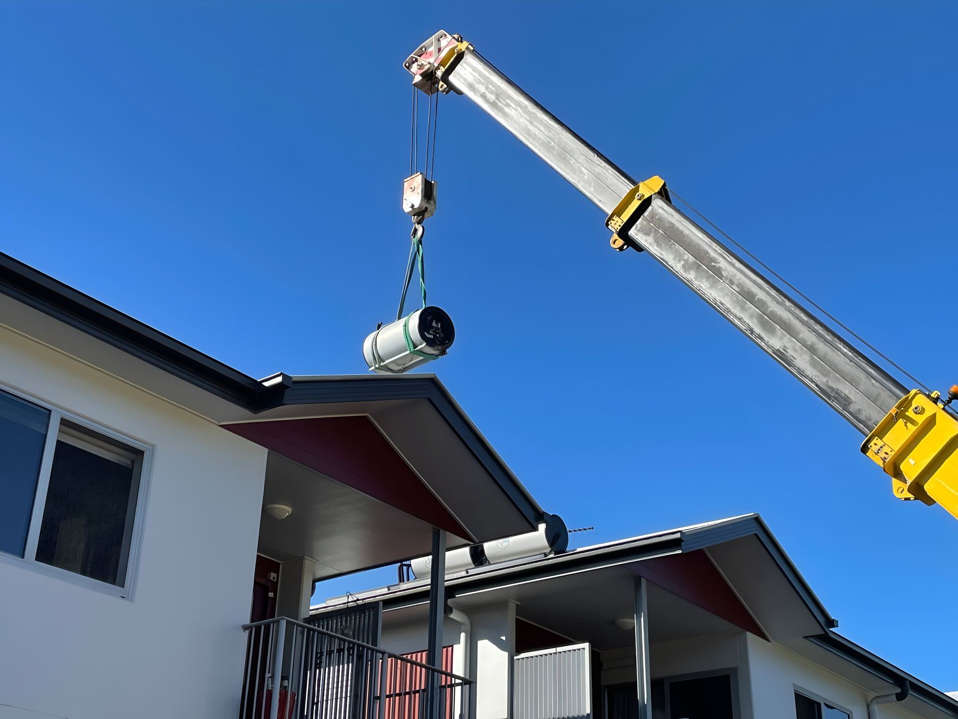 A Crane Lifting a Cylindrical Object Onto the Roof — Taps 'R' Us in Caboolture, QLD