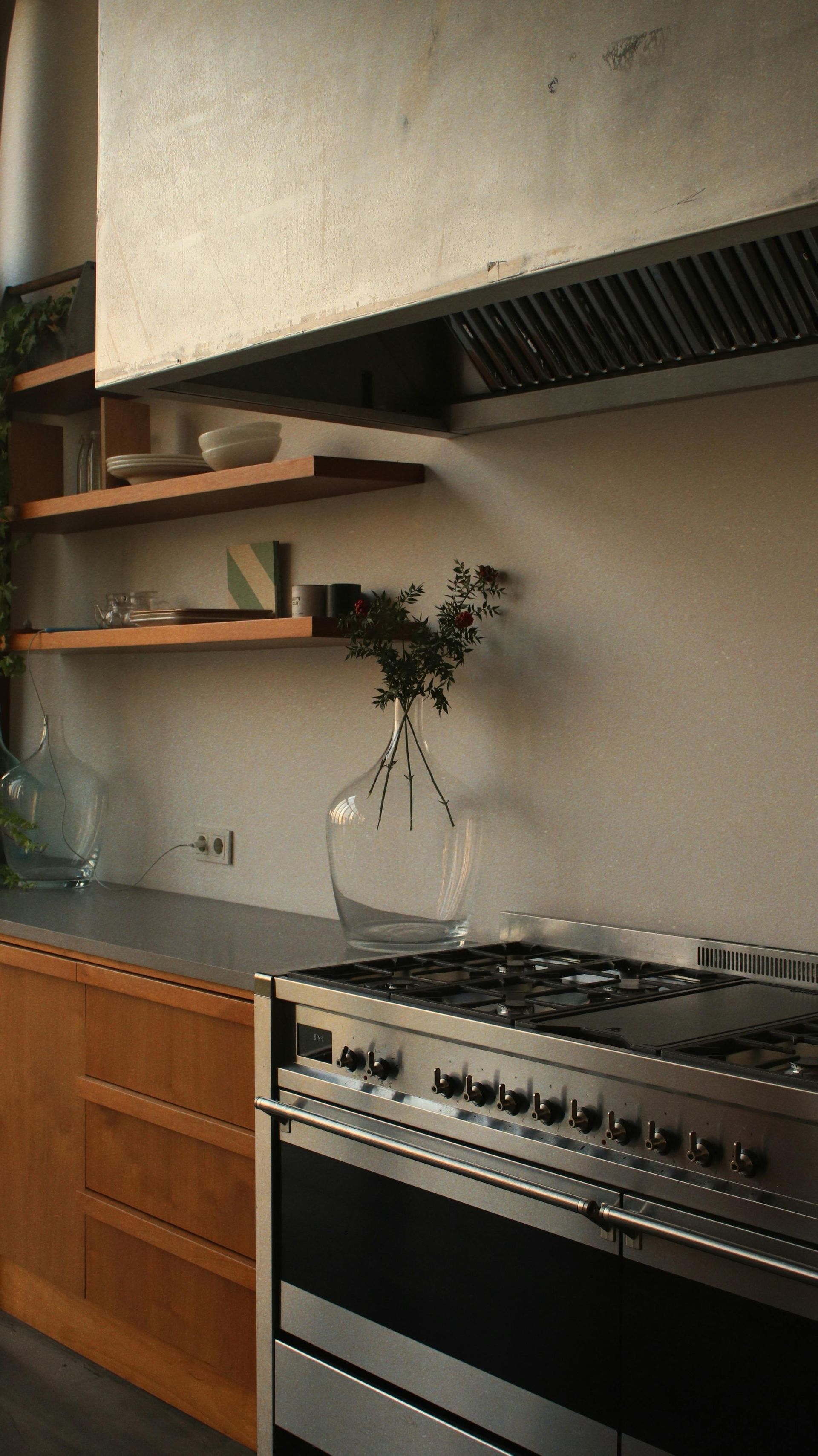 Kitchen with stainless steel range, wooden cabinets and shelves, and a clear vase with greenery. — Taps 'R' Us in Kunda Park, QLD