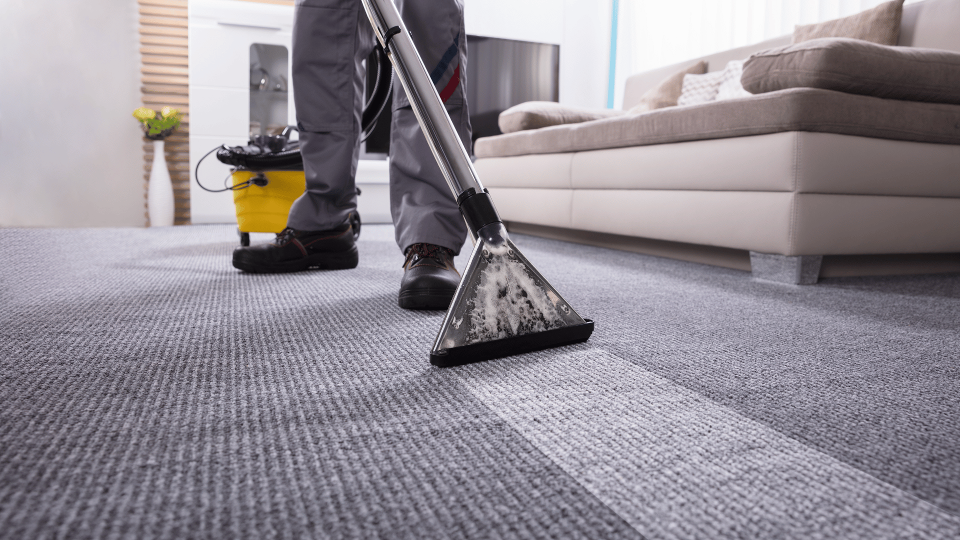 a man is using a vacuum cleaner to clean a carpet in a living room .