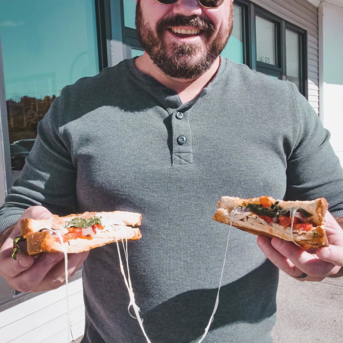 A man in a red shirt is holding a tray of sandwiches.