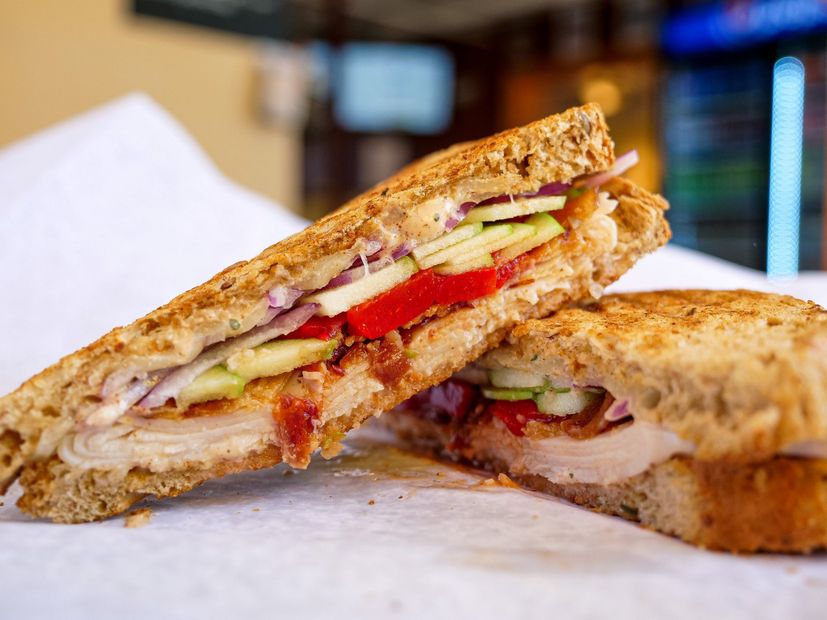 A person is holding a sandwich that has been cut in half.