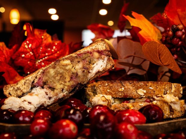 A grilled sandwich is cut in half on a piece of wax paper