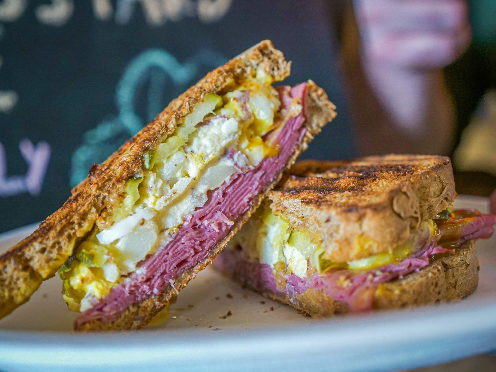 A person is holding a sandwich that has been cut in half.