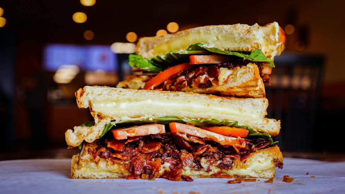 A person is holding a sandwich that has been cut in half.