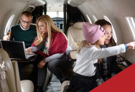 Passengers using a laptop and tablet inside a private jet cabin