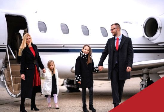 Family stepping off a private jet, with a woman, two children, and a man on the tarmac.