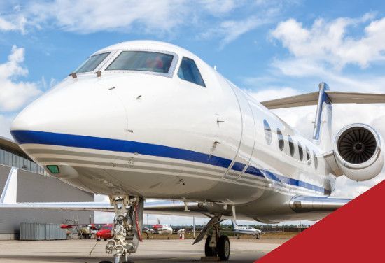 White private jet with blue stripes on airport tarmac under a cloudy sky